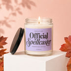 Scented candle labeled "Official Spellcaster" with the lid off, on a white cube.