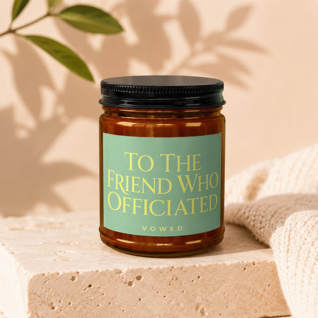 A candle with a teal label reading "To the friend who officiated" and "vowed."