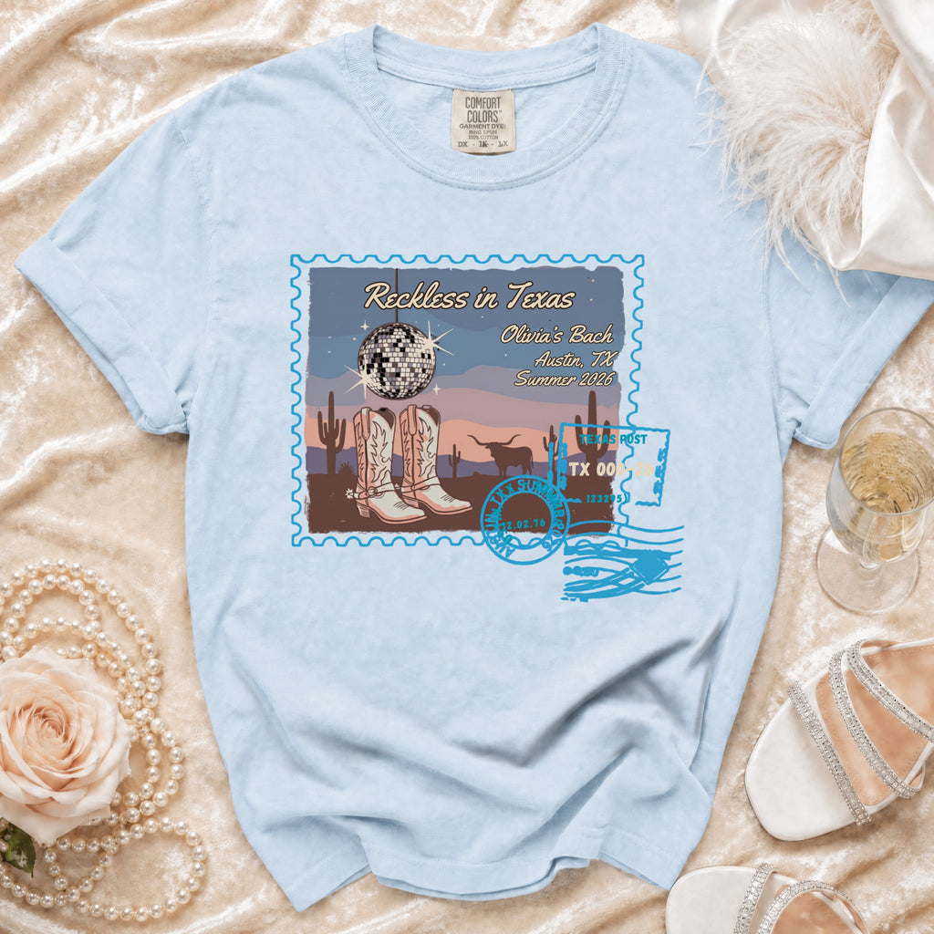 Light blue Comfort Colors t-shirt with "Reckless in Texas" graphic.