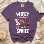 Purple t-shirt with "WIFEY Wants a Spritz" graphic and bachelorette party icons.