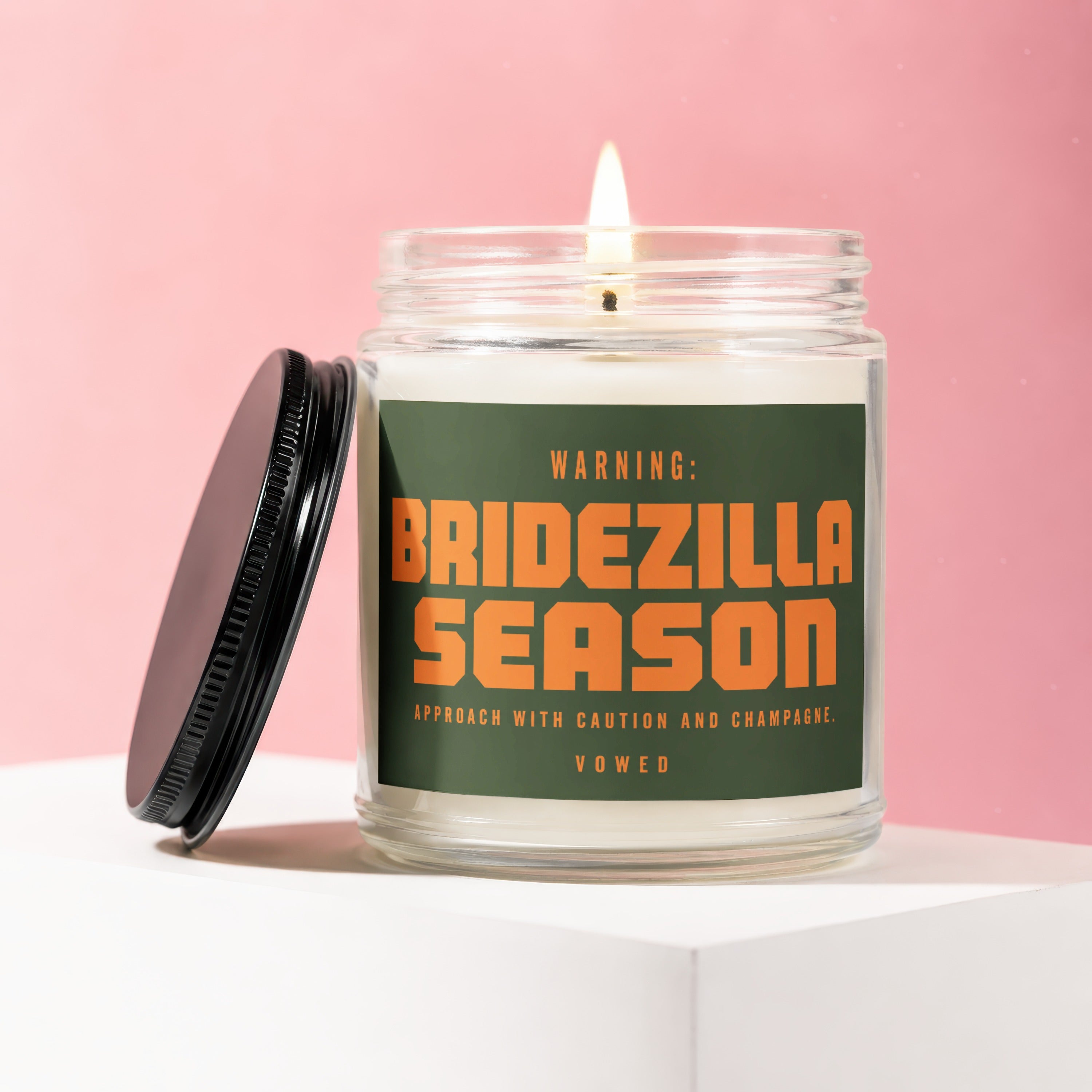 Jar candle with lit flame, featuring text "WARNING: BRIDEZILLA SEASON APPROACH WITH CAUTION AND CHAMPAGNE. VOWED".