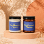 Two candles labeled "Hard Launch: Fiancé." on blue labels with black lids.