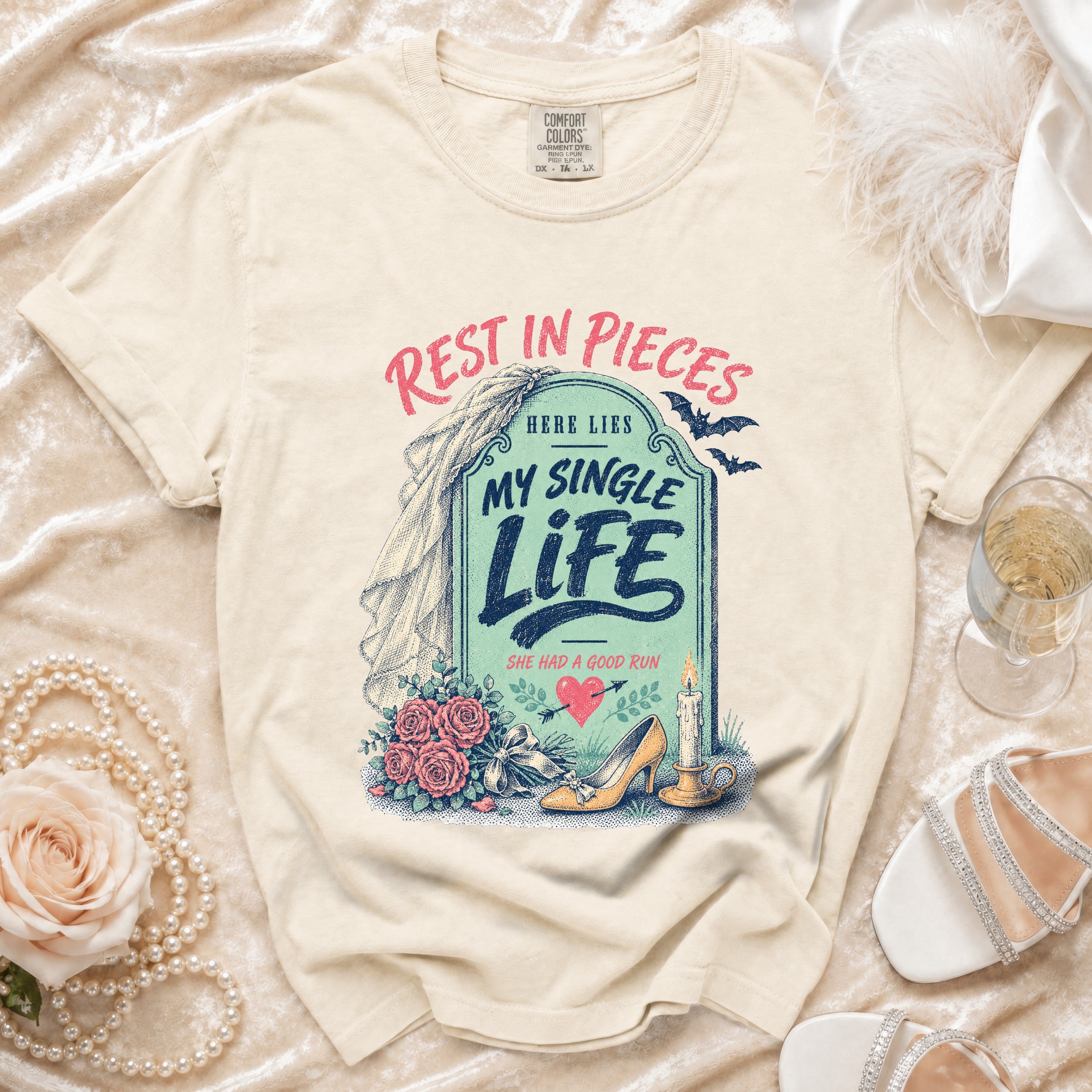 Cream t-shirt graphic with tombstone reading "Rest in Pieces Here Lies My Single Life She Had a Good Run".