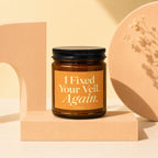Brown glass candle with orange label reading "I Fixed Your Veil. Again. VOWED"