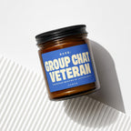 Amber jar candle with blue label reading "RANK: GROUP CHAT VETERAN"