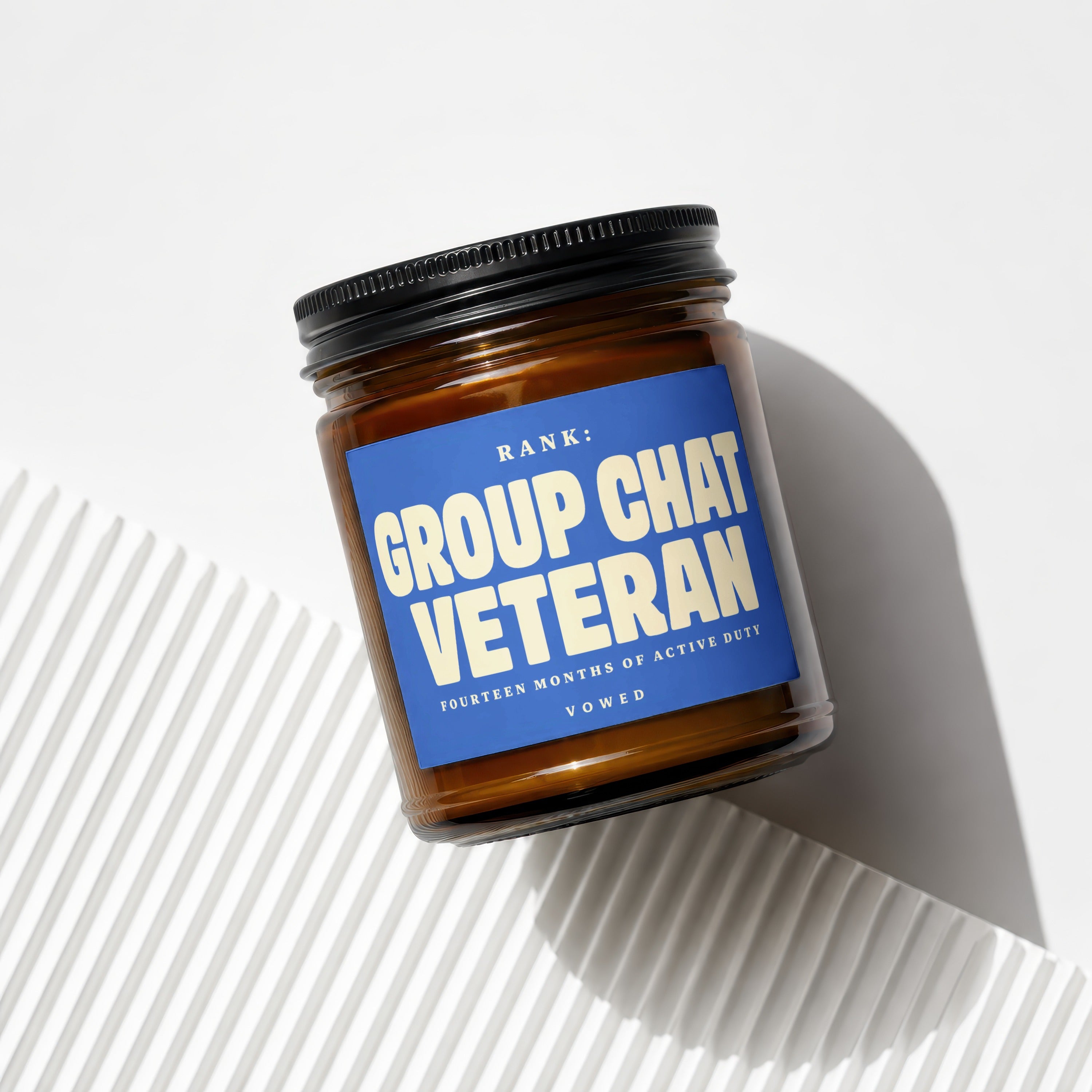 Amber jar candle with blue label reading "RANK: GROUP CHAT VETERAN"