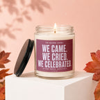 Glass candle with "We Came. We Cried. We Celebrated." text and a lit wick.