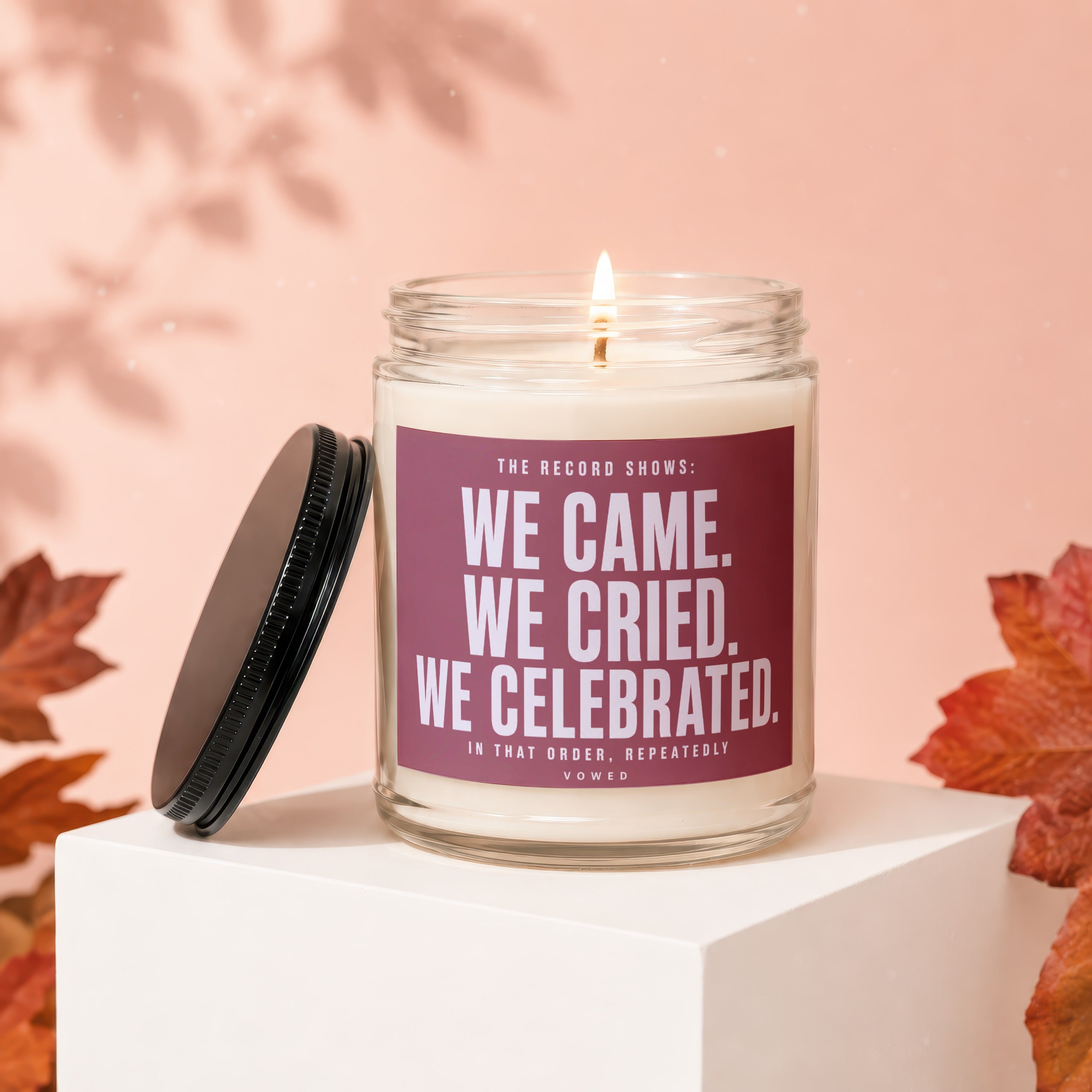 Glass candle with "We Came. We Cried. We Celebrated." text and a lit wick.
