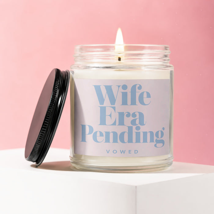 Lit candle with "Wife Era Pending Vowed" text on a light pink label.