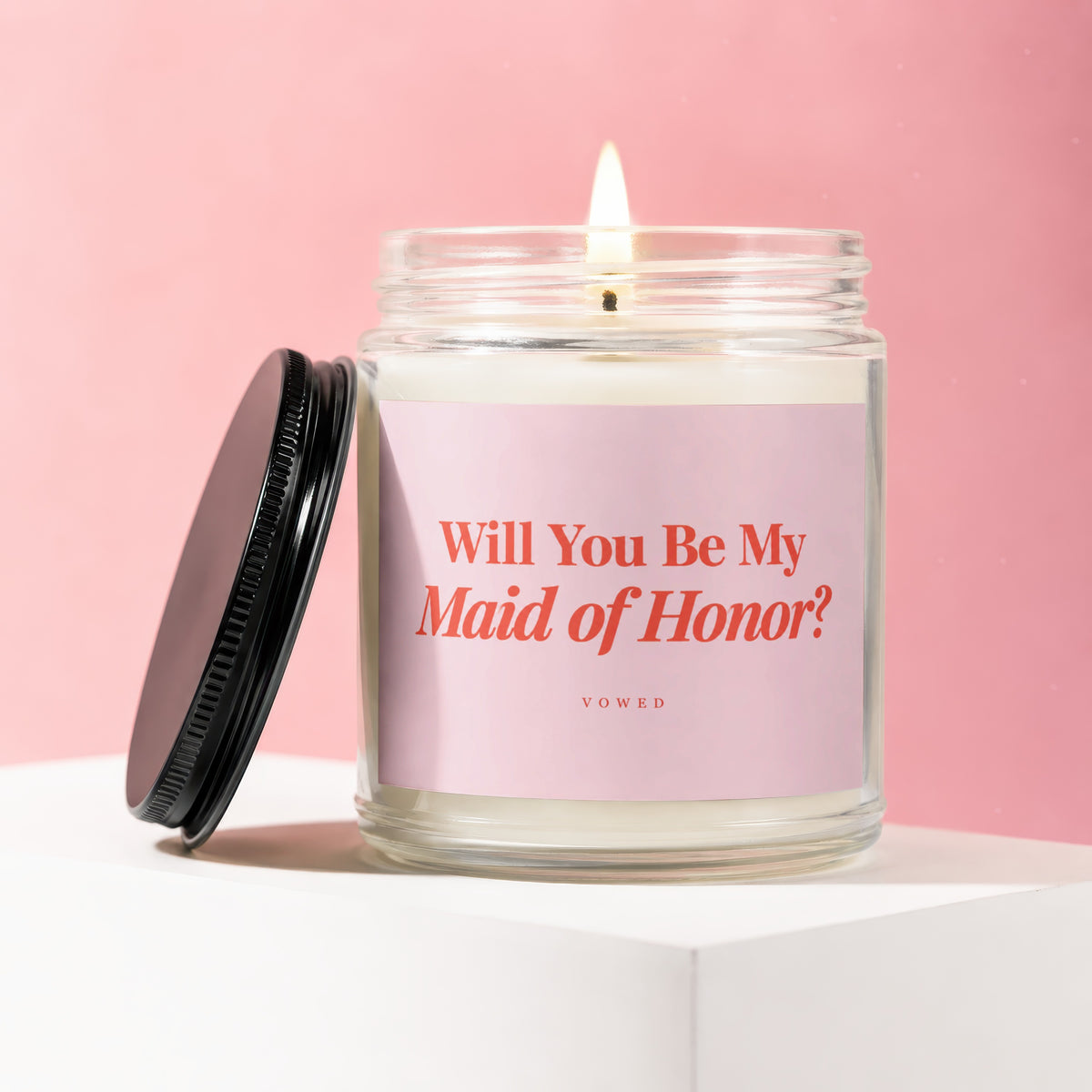 Lit candle in a jar with a pink label asking "Will You Be My Maid of Honor?".