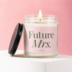 Lit candle in a glass jar with a black lid, labeled "Future Mrs. Vowed" on a pink background.