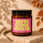Amber jar candle on a stone block with pink label that reads "You're Stuck With Me".