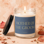 Glass jar candle with a lit wick and a blue label reading "MOTHER OF THE GROOM. VOWED".