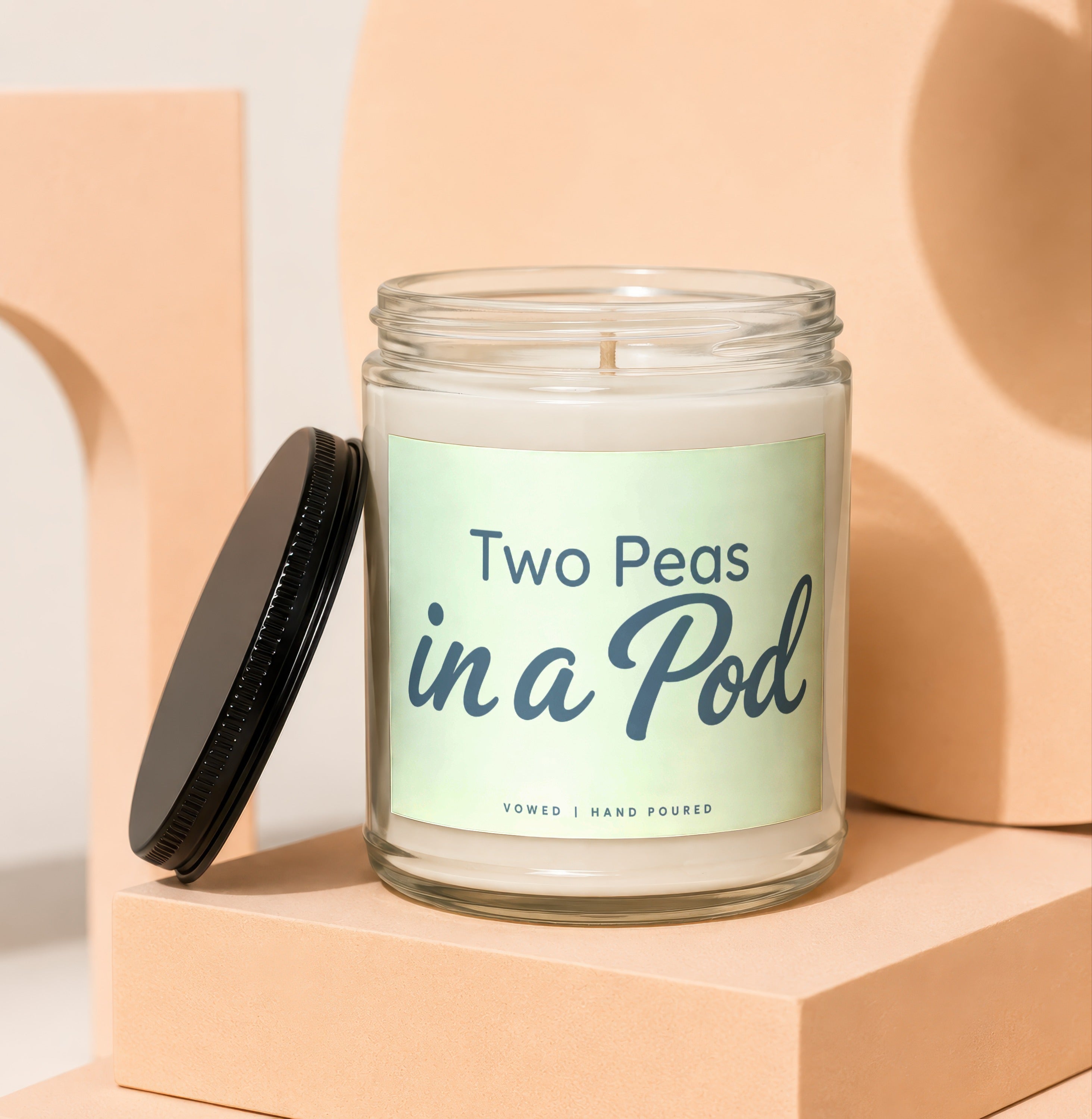 Glass jar candle with "Two Peas in a Pod" label, black lid off.