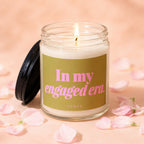 Lit candle in glass jar with black lid, reads "In my engaged era."