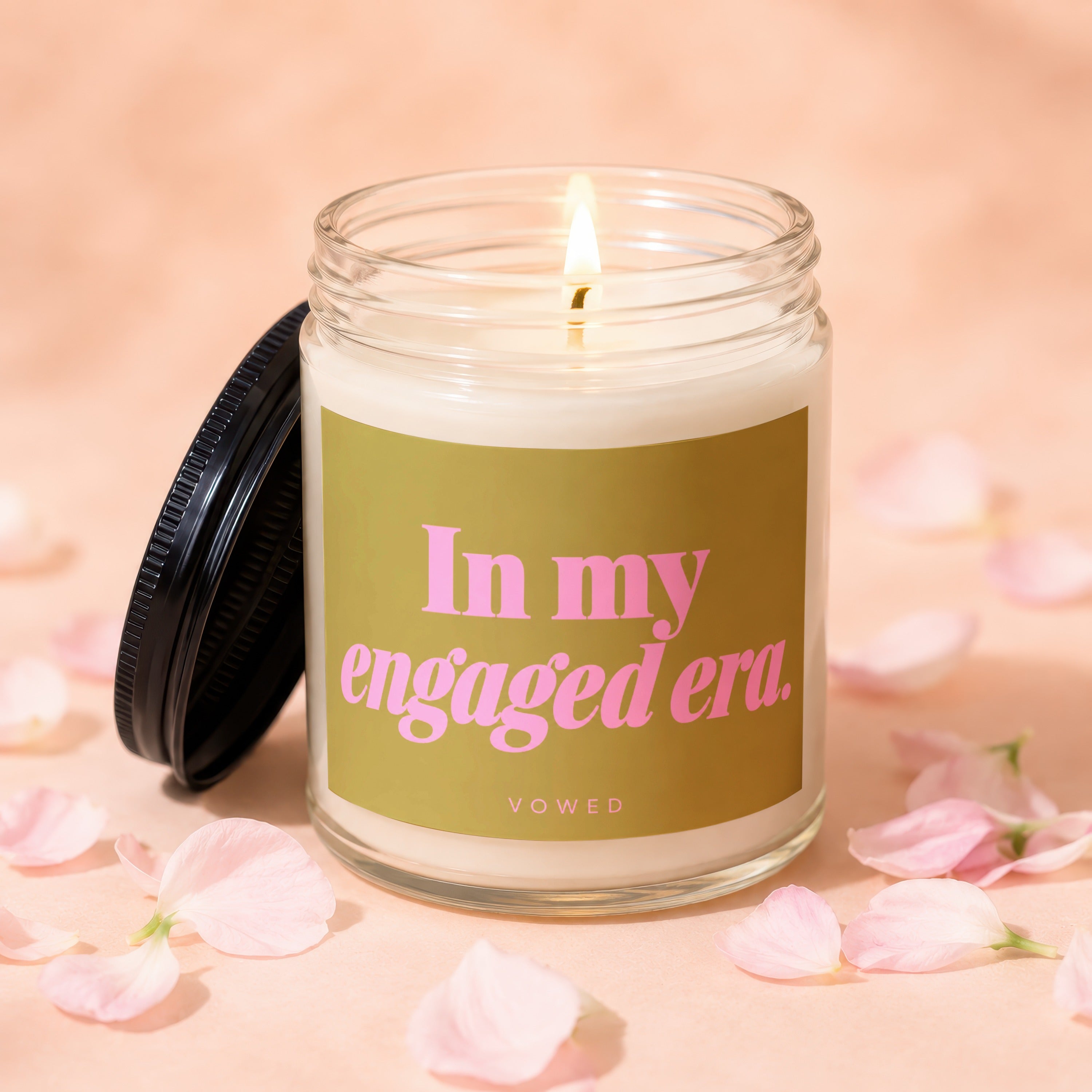 Lit candle in glass jar with black lid, reads "In my engaged era."