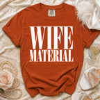 Orange t-shirt with "WIFE MATERIAL" printed in white text.