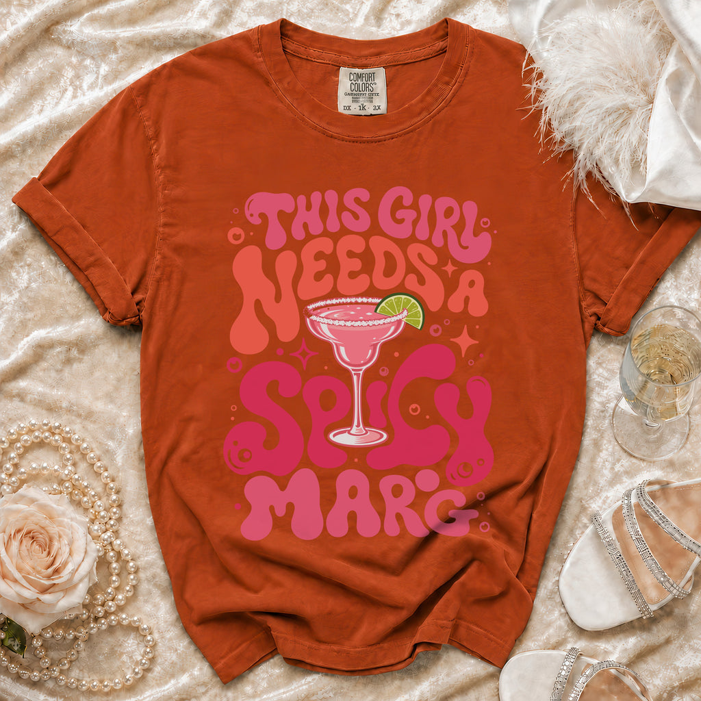 Orange t-shirt with pink text "This girl needs a Spicy Marc" and margarita image.