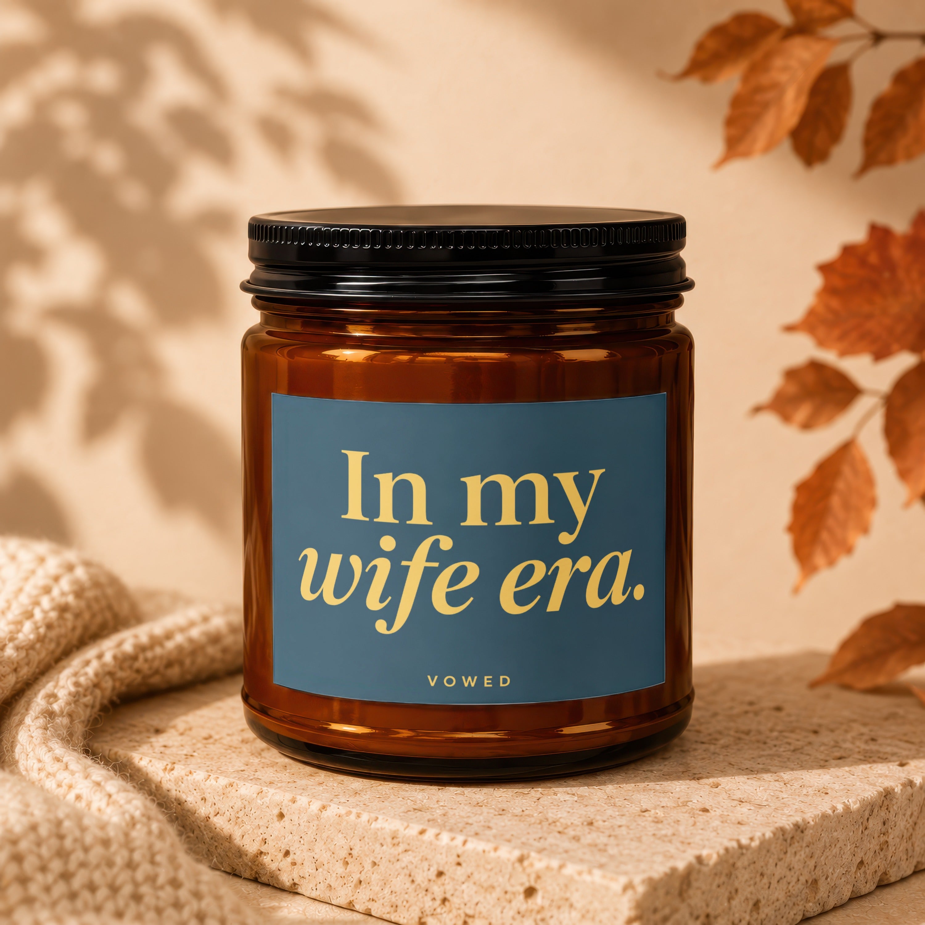 Amber jar candle with navy label saying "In my wife era."