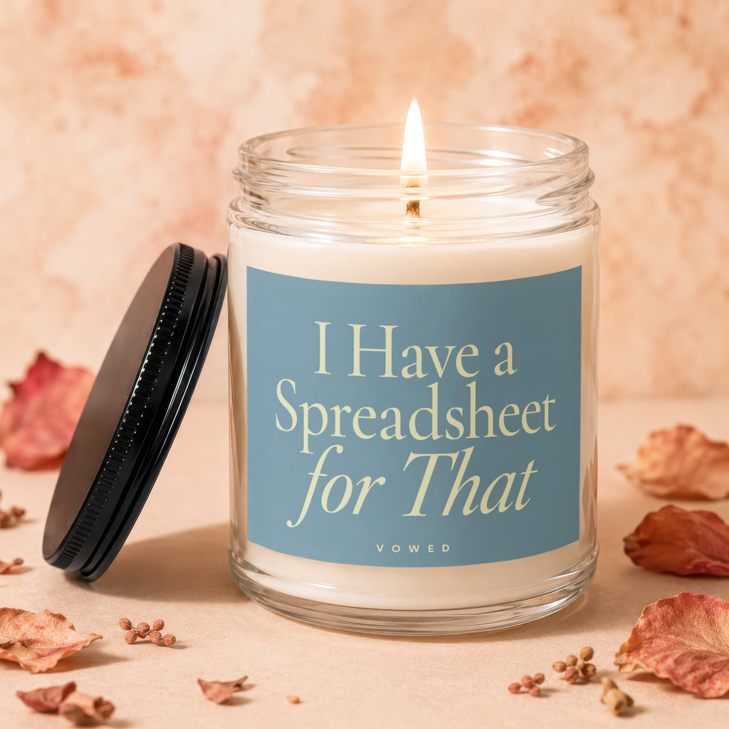 Lit candle in a glass jar with a blue label that reads "I Have a Spreadsheet for That".