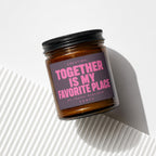 Amber glass candle with dark lid, reads "LOCATION: TOGETHER IS MY FAVORITE PLACE"