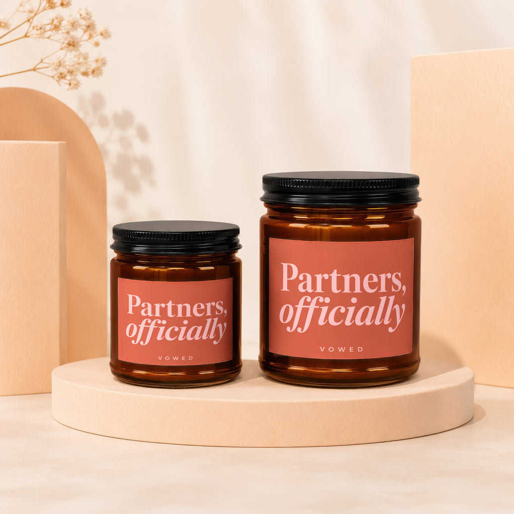 Two amber glass candles with black lids, one larger than the other.