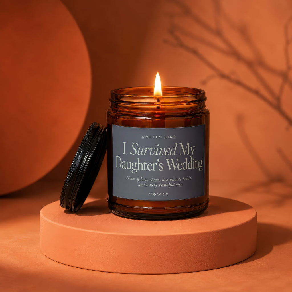 Amber jar candle with lit flame, label reads "I Survived My Daughter's Wedding".