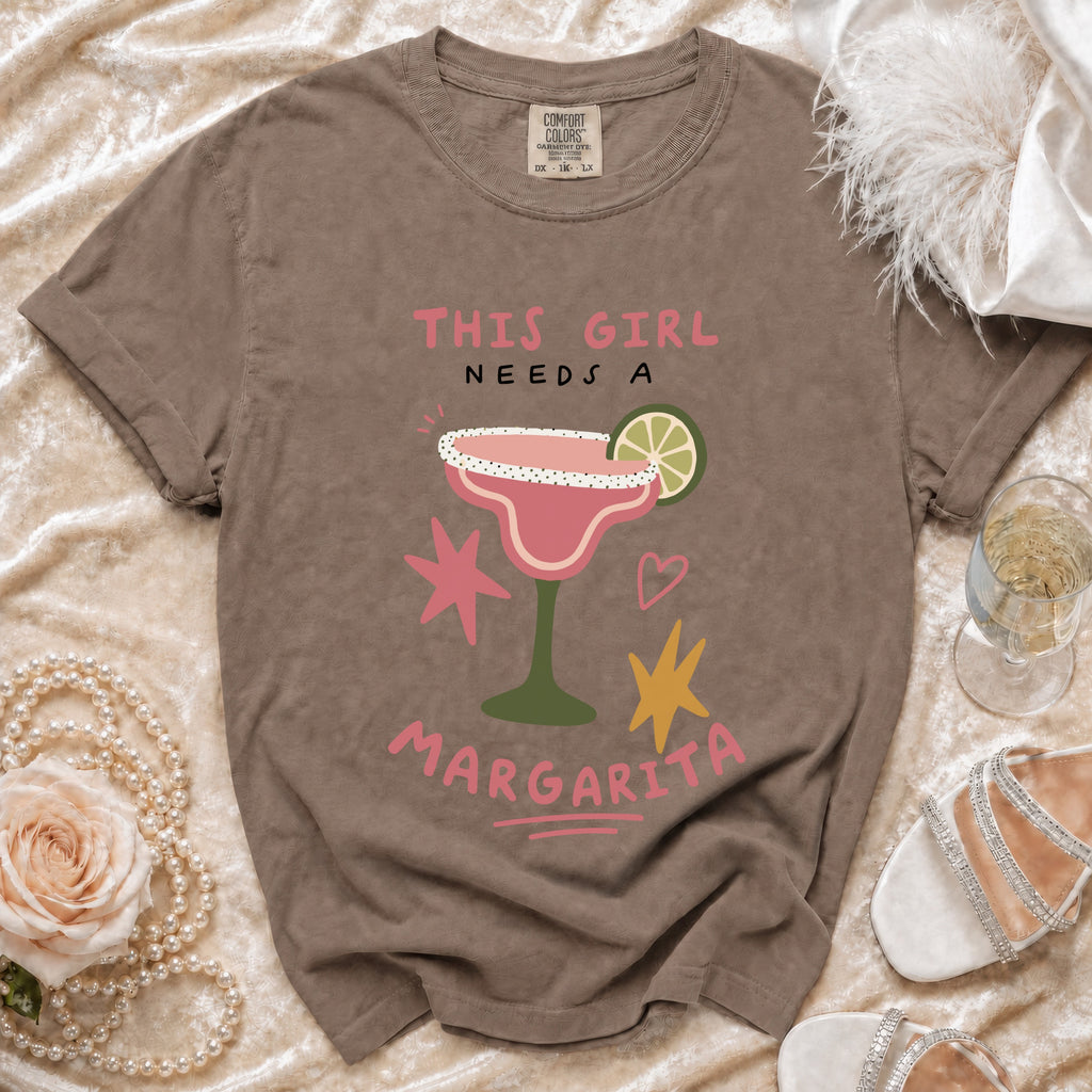 Brown t-shirt with "This Girl Needs A Margarita" graphic of a pink cocktail.
