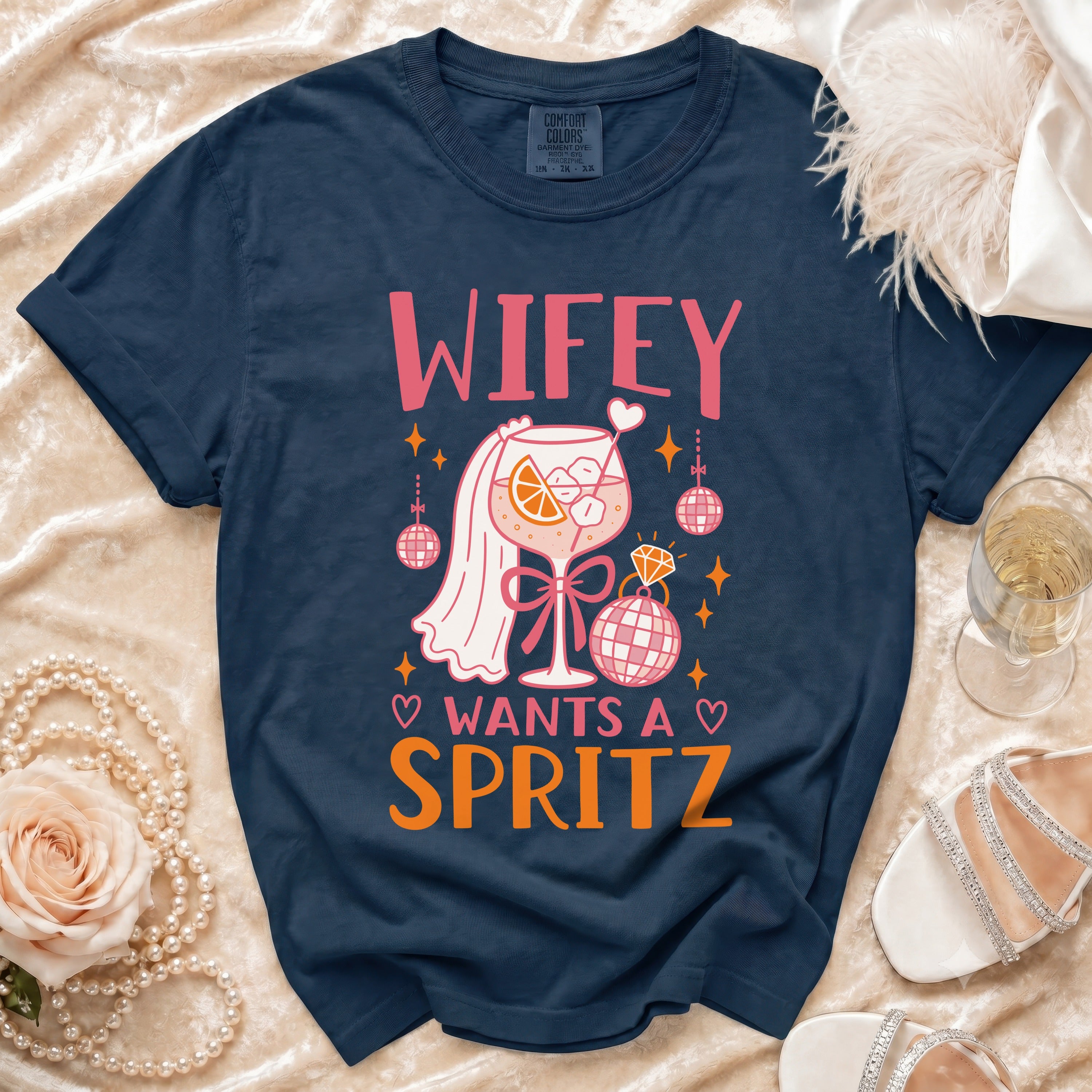 Navy t-shirt with pink text "WIFEY WANTS A SPRITZ" and cocktail graphic.