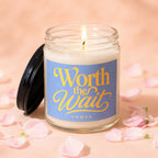Candle with "Worth the Wait" text on label, surrounded by pink petals.