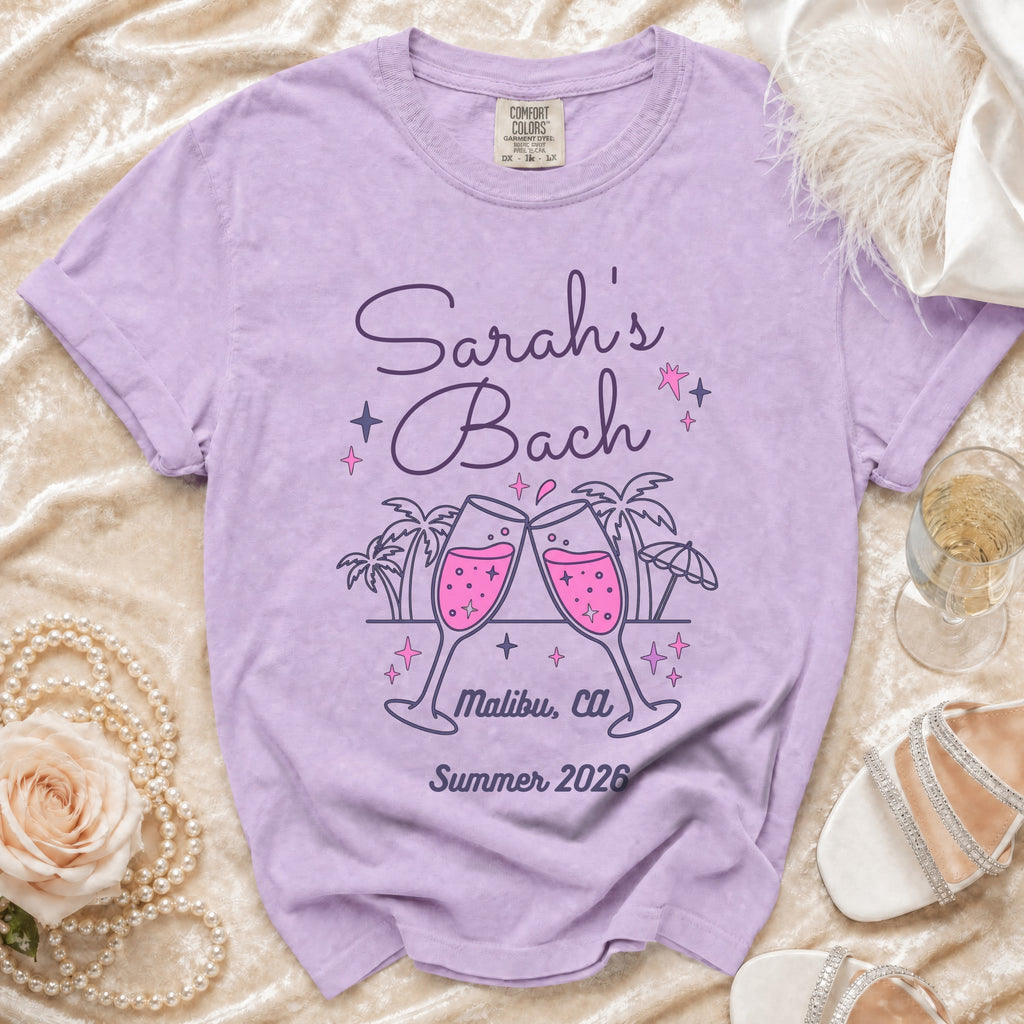 Purple t-shirt with "Sarah's Bach Malibu, Ca Summer 2026" text and toasting champagne glasses.