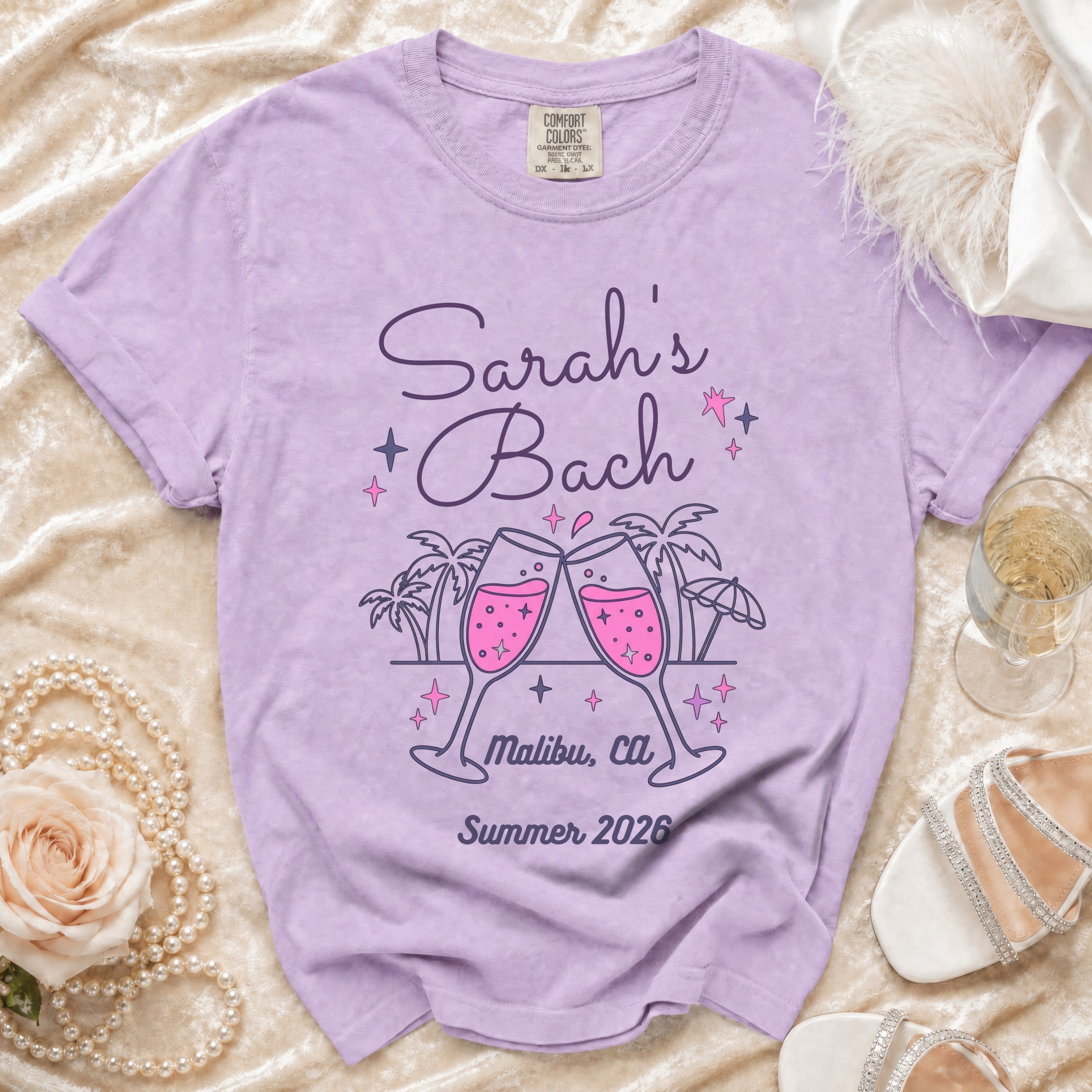 Purple t-shirt with "Sarah's Bach Malibu, Ca Summer 2026" text and toasting champagne glasses.