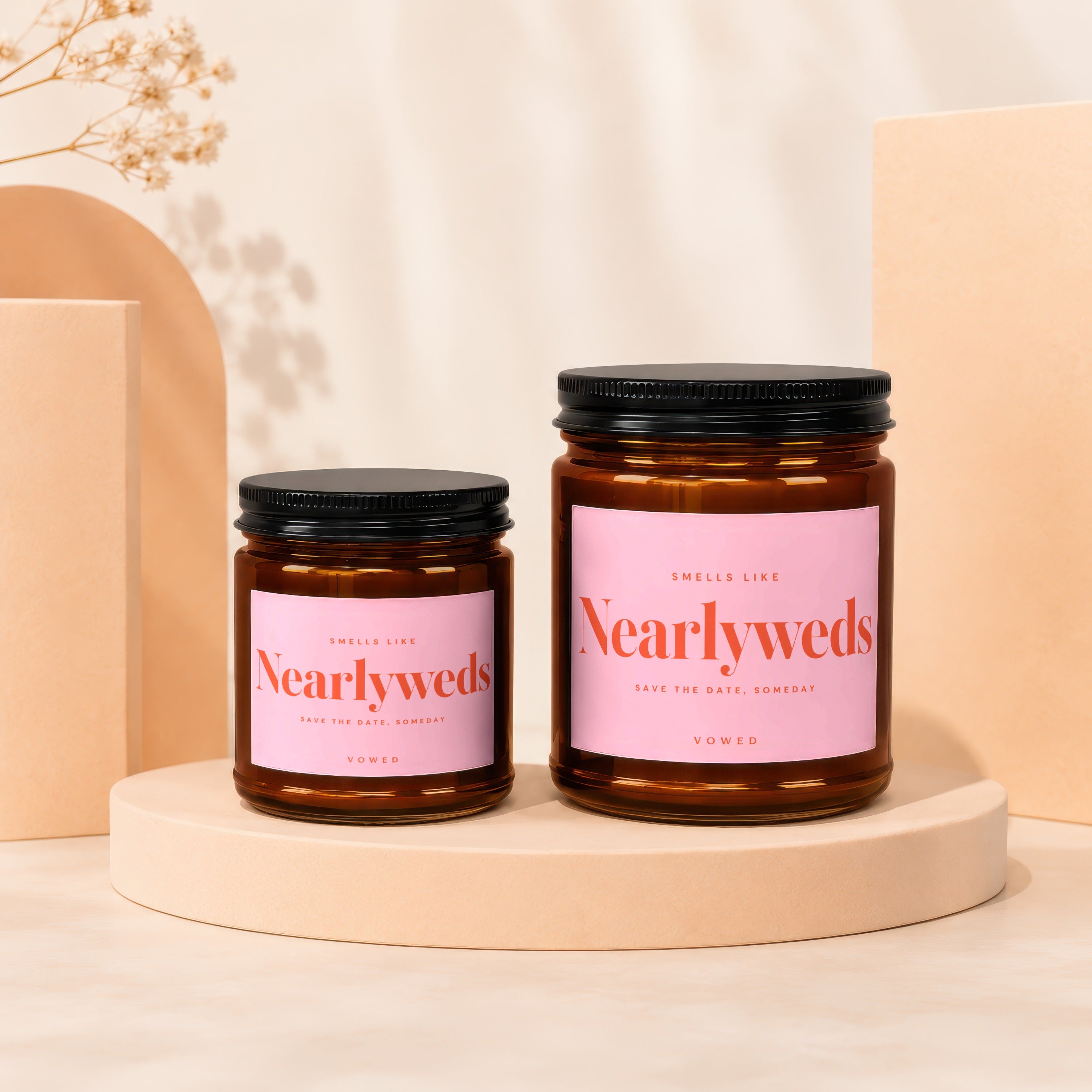 Two amber glass candles with pink labels reading "Nearlyweds" and "Vowed".