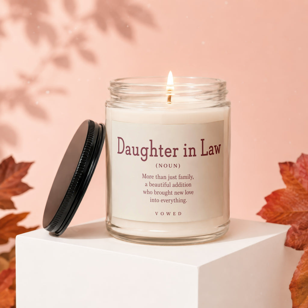 Candle with "Daughter in Law" definition on label, lid off and on pedestal.