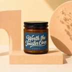 Brown glass candle with dark blue label reading "Worth the Toaster Oven" and "VOWED".