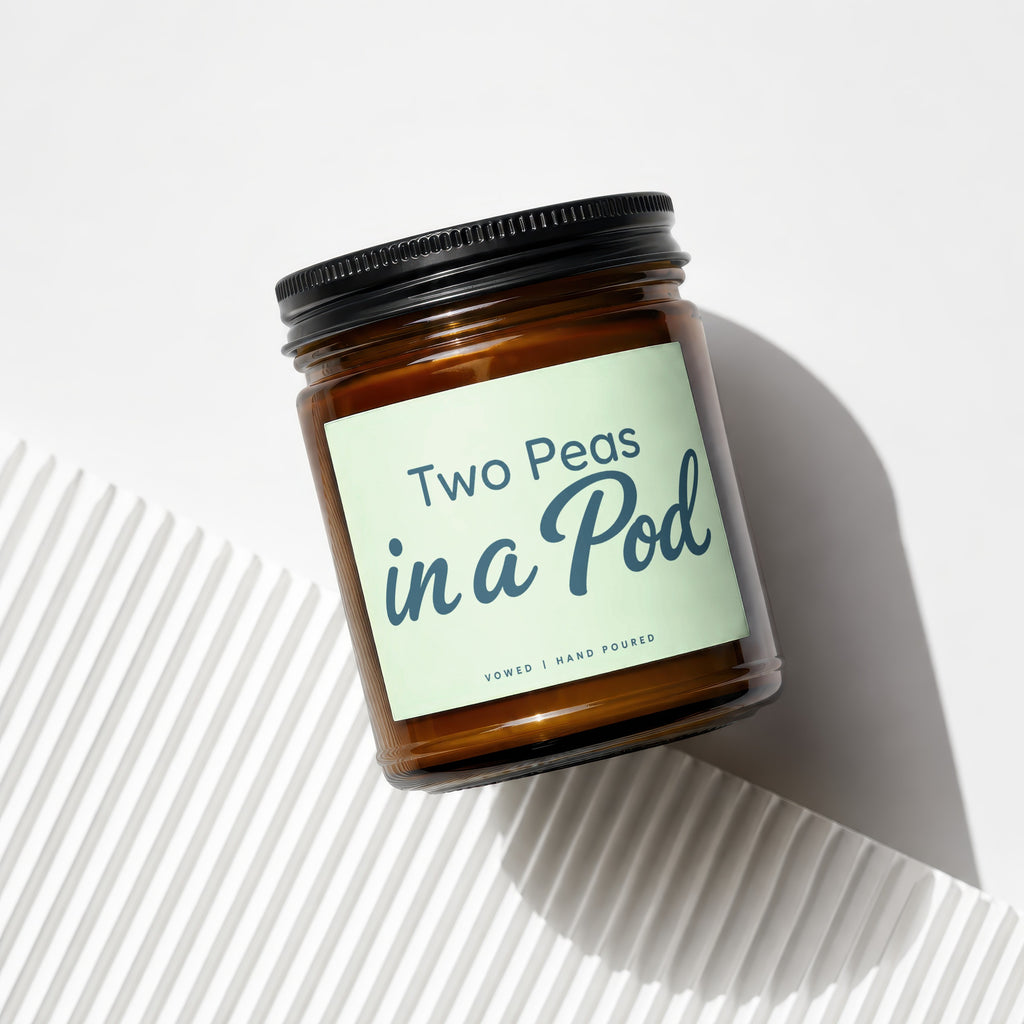 Amber candle in a jar labeled "Two Peas in a Pod | VOWED | HAND POURED".