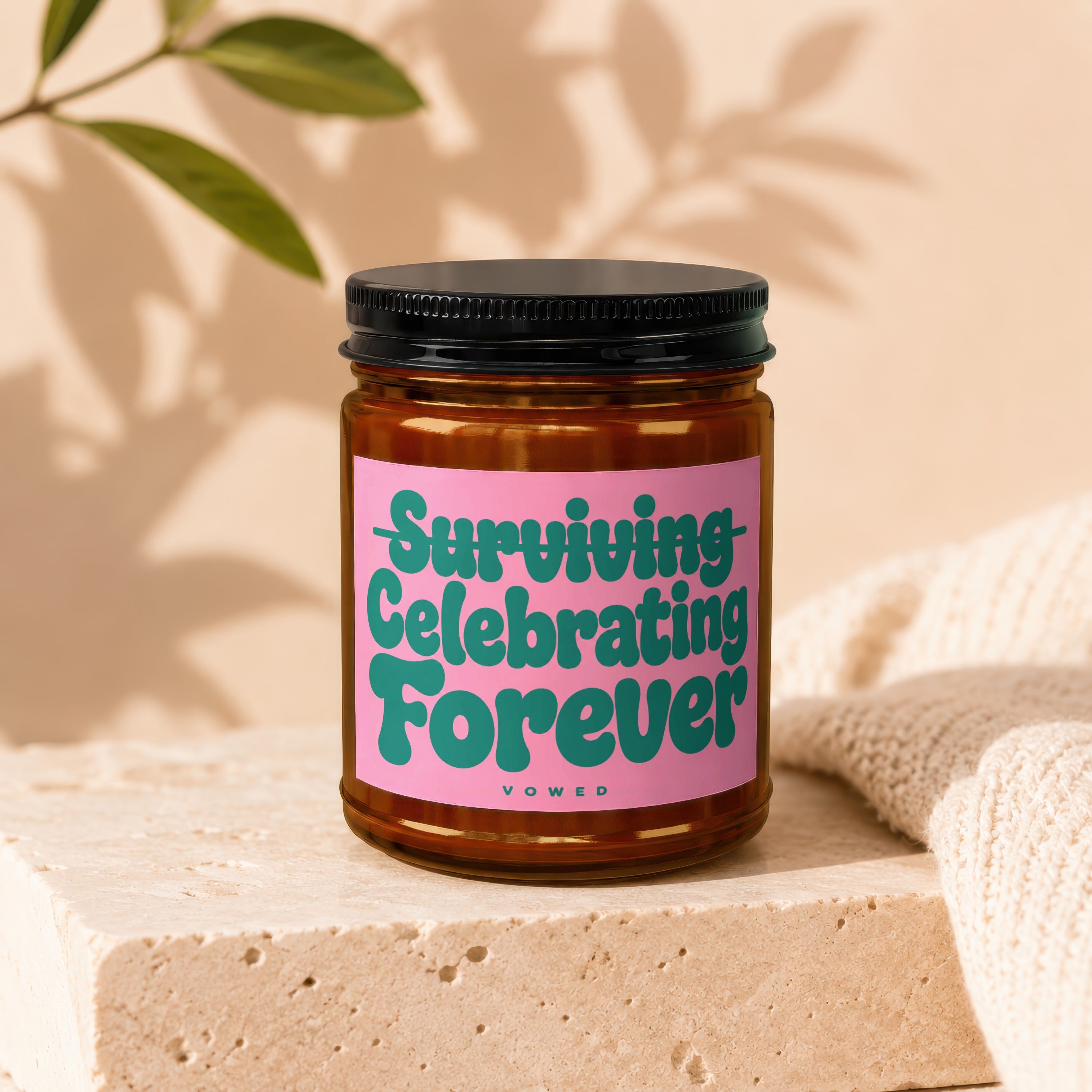 Brown glass candle with pink label reading "Surviving Celebrating Forever Vowed".