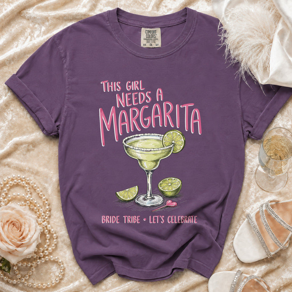 Purple t-shirt with margarita graphic and text: "This Girl Needs A Margarita. Bride Tribe Let's Celebrate."