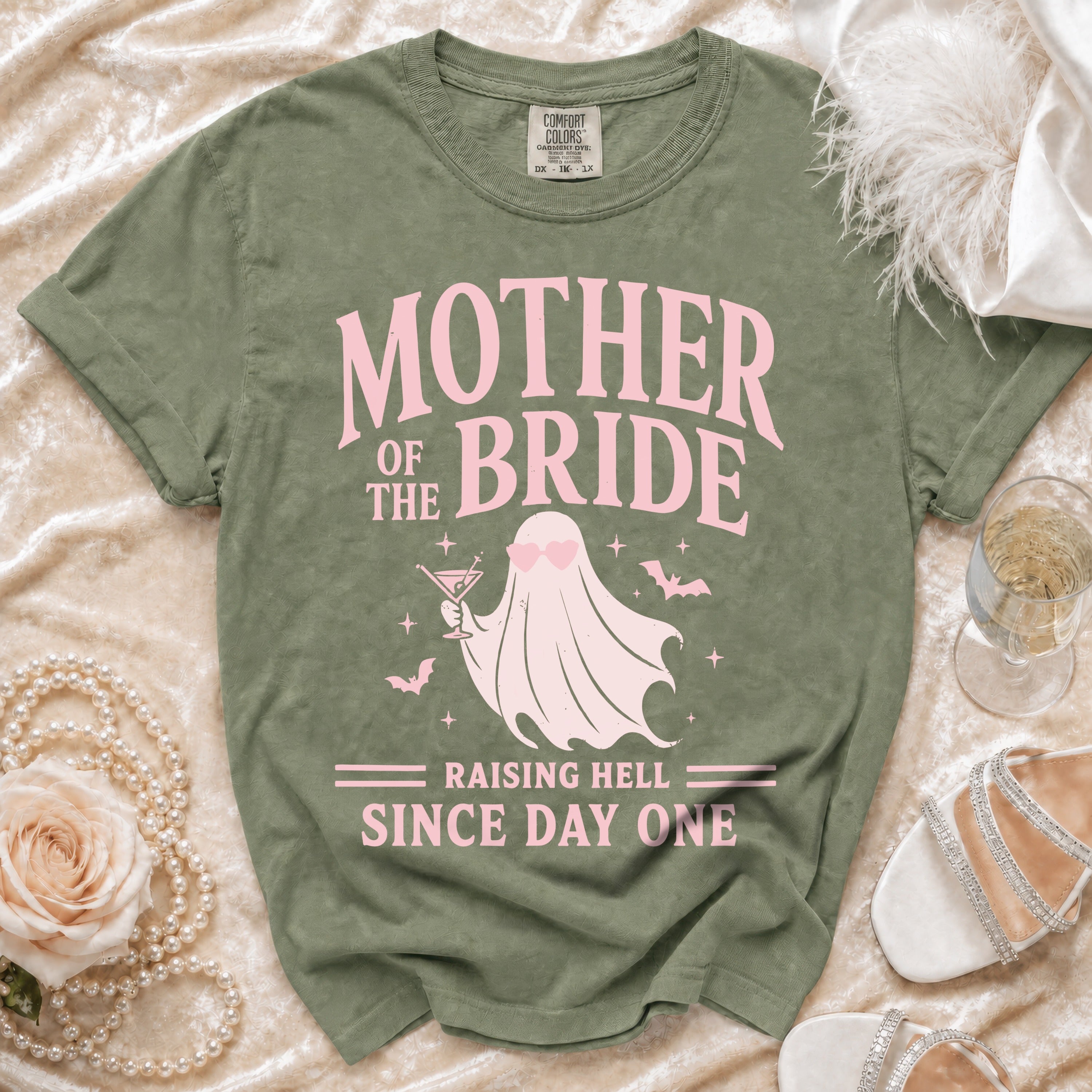 Green t-shirt with pink text "Mother of the Bride Raising Hell Since Day One" and a ghost graphic.