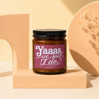 Amber glass candle with a maroon label that reads "Yaaas we said I do" and "VOWED".