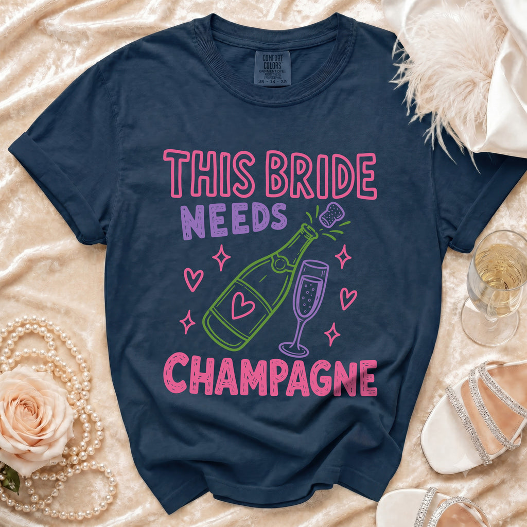 Navy t-shirt with "This Bride Needs Champagne" graphic and champagne bottle and coupe.