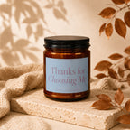 Amber glass candle with black lid and "Thanks for Choosing Me" label.