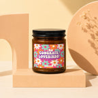 Amber jar candle with "Congrats, Lovebirds! On Your Engagement" text and floral design.