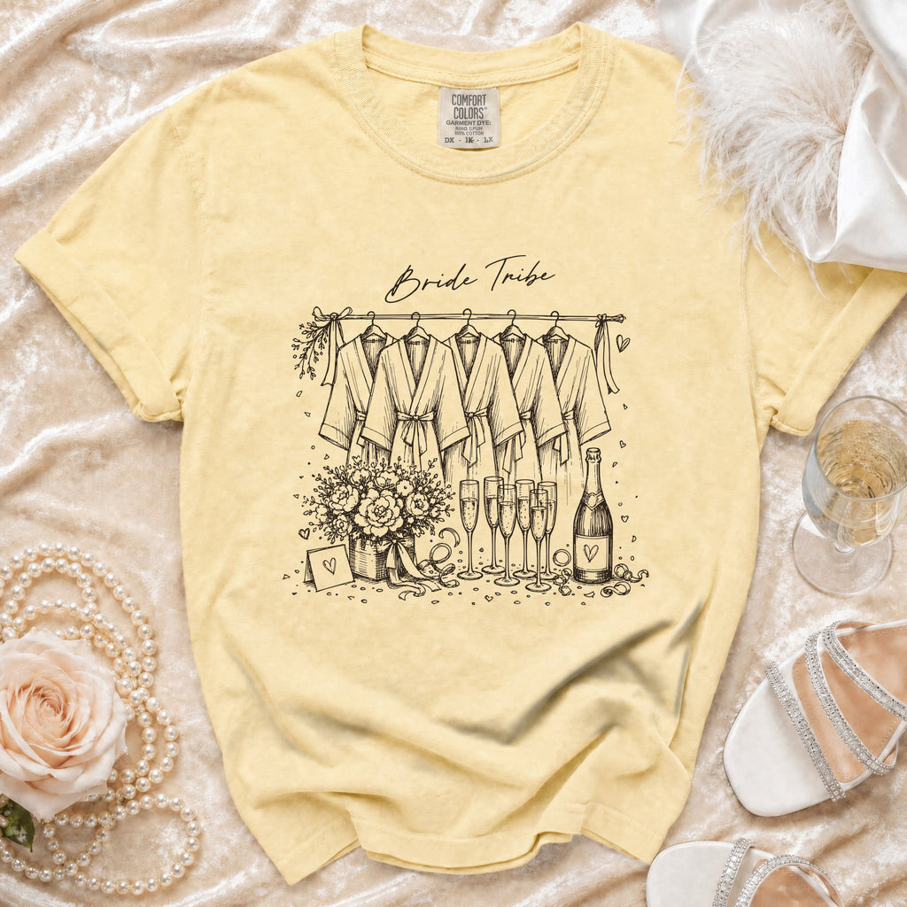 Yellow t-shirt with "Bride Tribe" text and sketch of robes, champagne, and flowers.