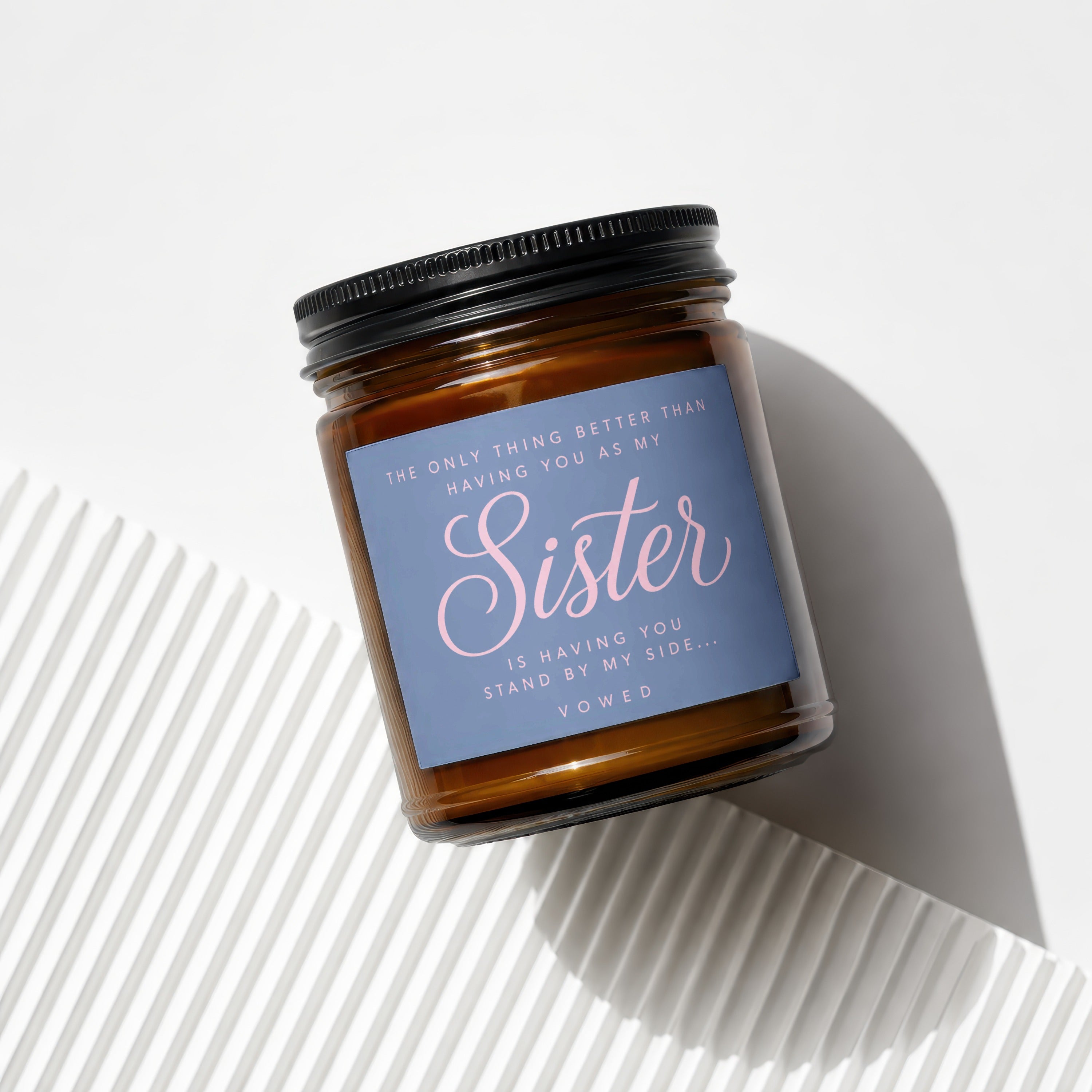 Amber candle with black lid and blue label reading "Sister" and quote.