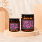 Two amber glass candles with black lids, featuring "Fabulous Mother of The Groom" text.