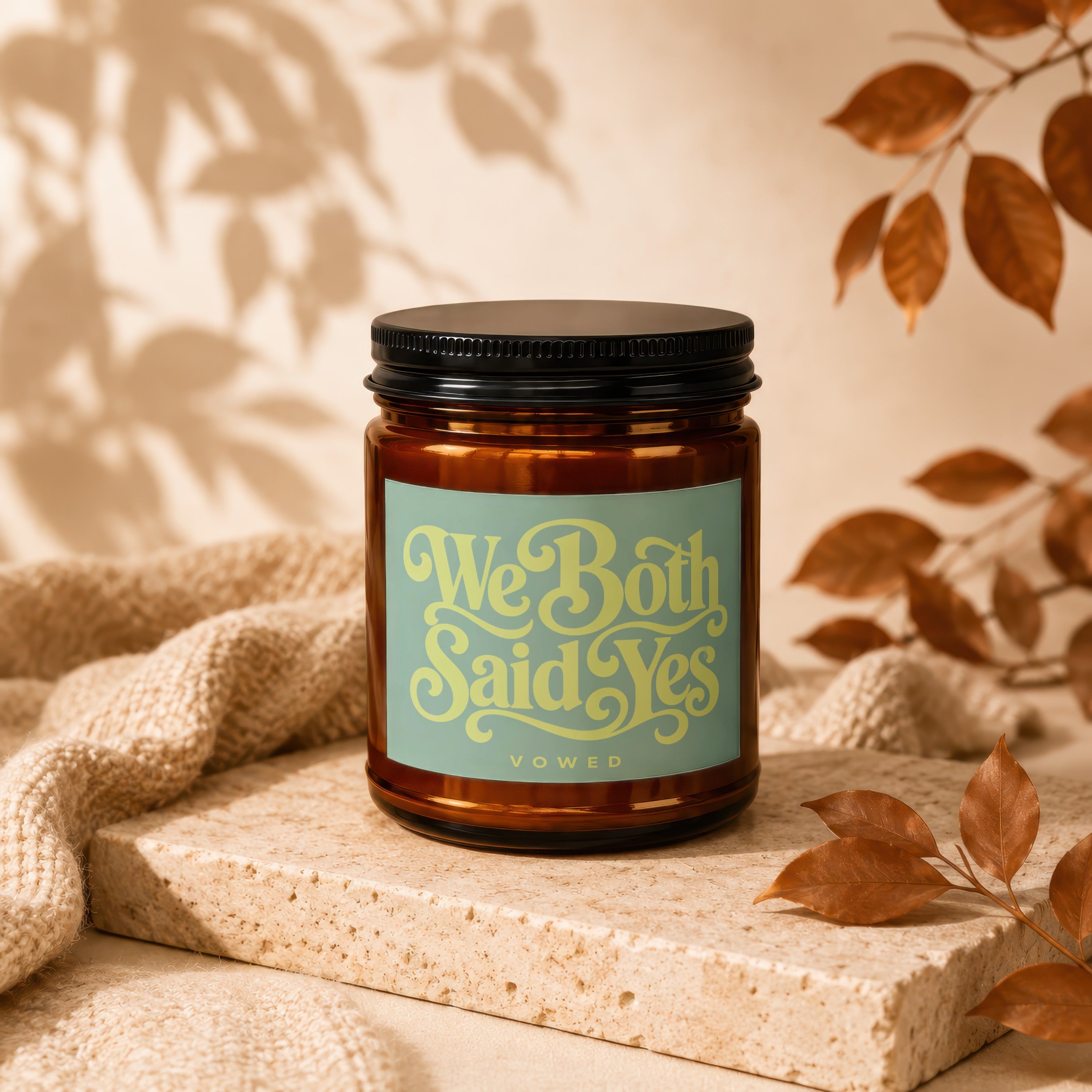 Amber candle with label reading "We Both Said Yes" on a stone block.