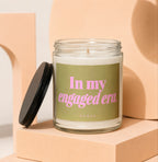 Glass candle with "In my engaged era" text on olive green label.