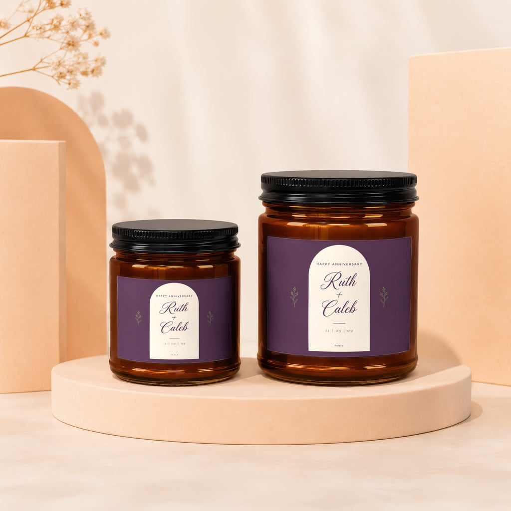 Two amber glass candles with black lids, featuring "Ruth + Caleb" anniversary labels.
