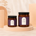 Two amber glass candles with black lids, featuring "Ruth + Caleb" anniversary labels.